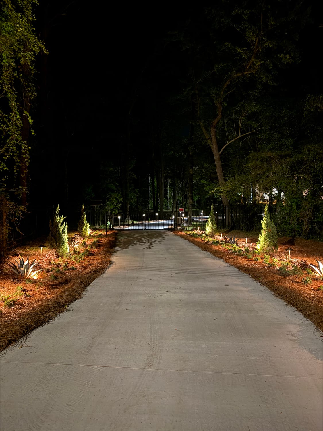 Path-lit driveway leading to an illuminated gate
