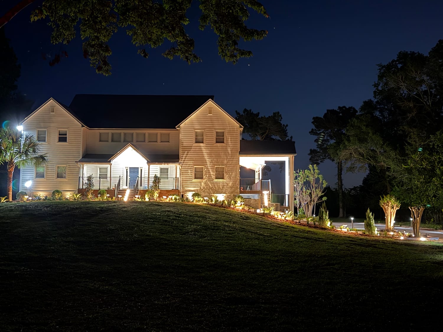 Home facade and landscape beds lit at dusk