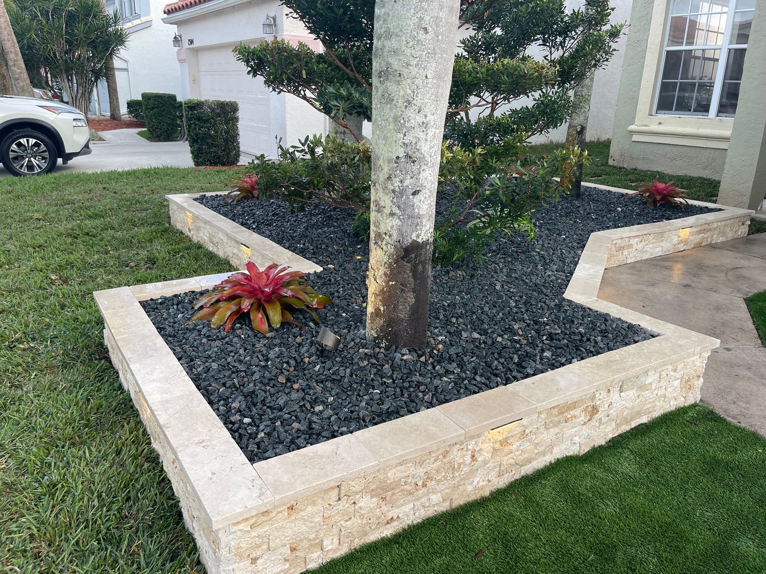 Stone tree surround with black lava rock and travertine edging