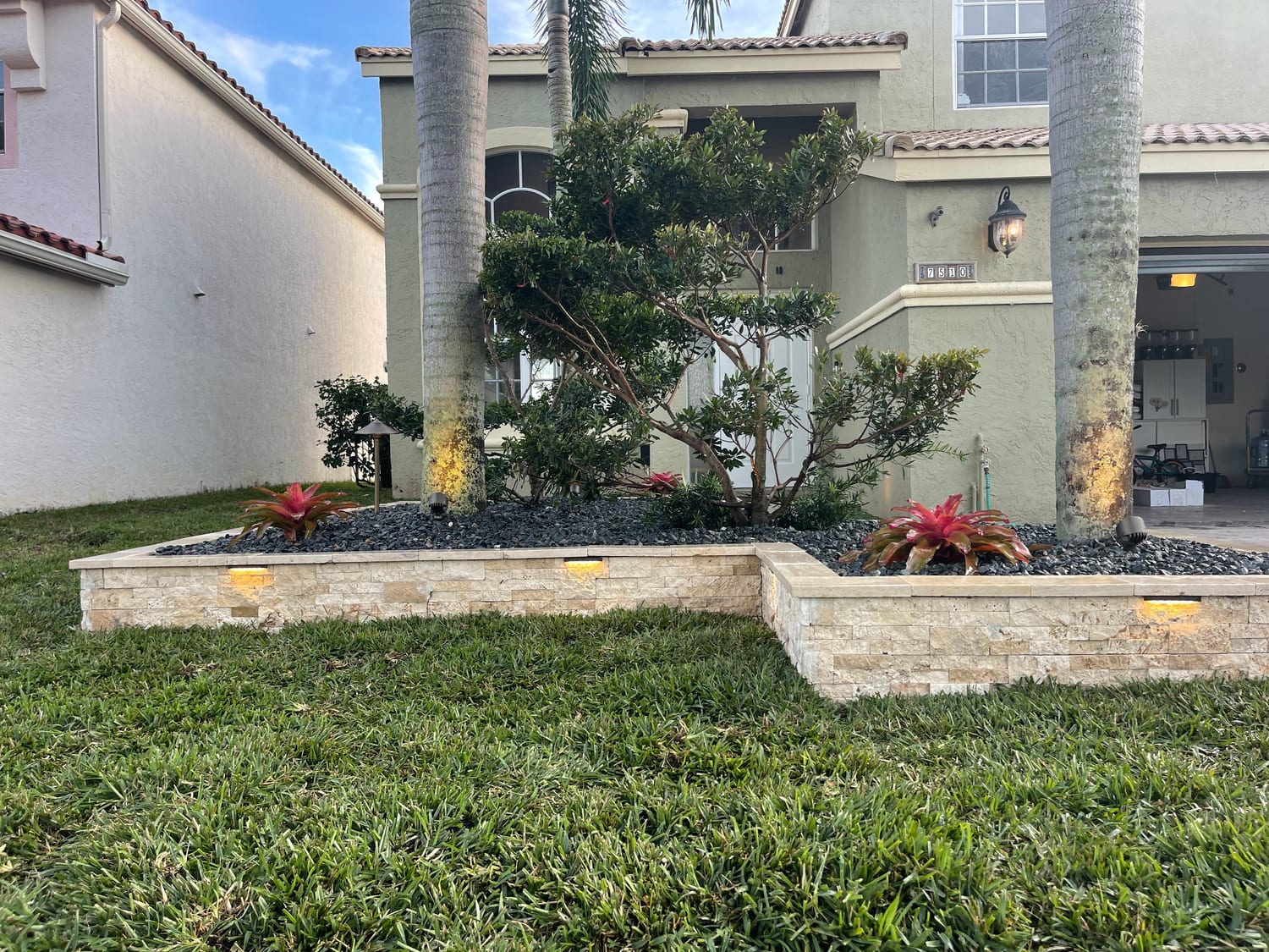 Stacked-stone raised planter bed with black rock at a home entrance